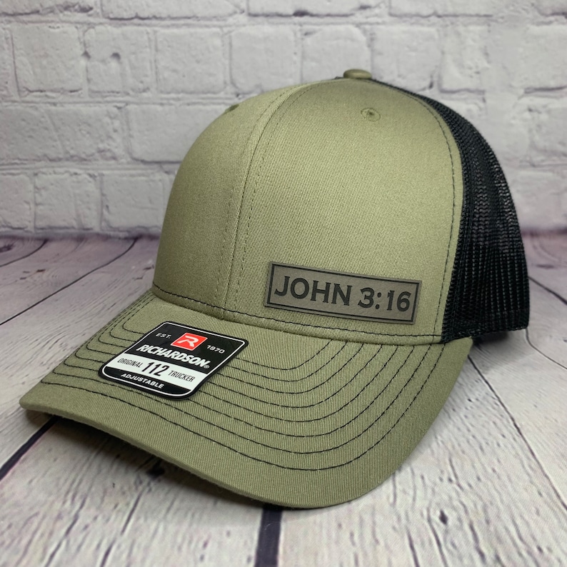 May include: A green and black trucker hat with a black leather patch that says "JOHN 3:16". The hat is adjustable and has a Richardson 112 logo.