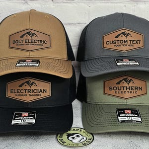 May include: A collection of baseball caps in various colors, including tan, black, gray, and olive green. Each cap features a leather patch with text related to electrical services, such as "Bolt Electric" and "Electrician."
