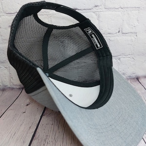 May include: A gray and black mesh trucker hat with a white label that says "Richardson 110" on the back.