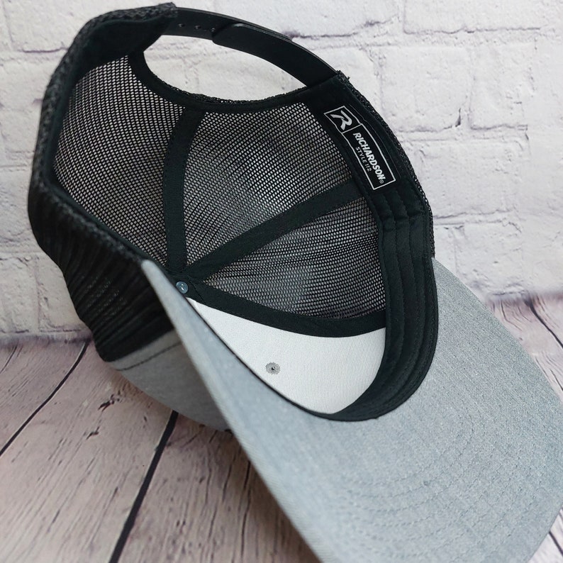 May include: A gray and black mesh trucker hat with a white label that says "Richardson 110" on the back.