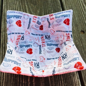 May include: White fabric bowl with a red heart and a blue medical mask pattern. The bowl is printed with the text "Nurses Care Support" and "Nurses Are The Real Heroes".