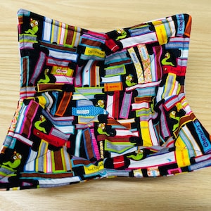 May include: A black quilted hot pad with a book and worm print. The print features colorful book spines with words like "English", "Dictionary", and "Chapter".