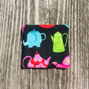 May include: A black fabric pouch with a colorful print of teapots and elephants. The teapots are red, green, and pink, and the elephants are blue and white.