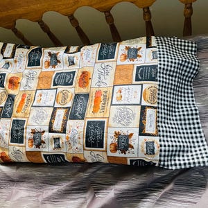 May include: A decorative pillow with a black and white checkered back and a front featuring a patchwork design of various fall-themed patterns with the words "Give Thanks", "Grateful", and "Pumpkins" printed on it.