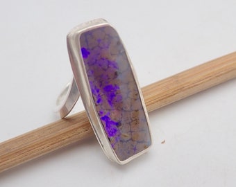 May include: A silver ring with a rectangular purple opal gemstone.