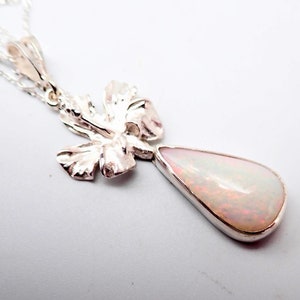 May include: A silver pendant necklace featuring a teardrop-shaped white opal gemstone and a delicate silver leaf design.