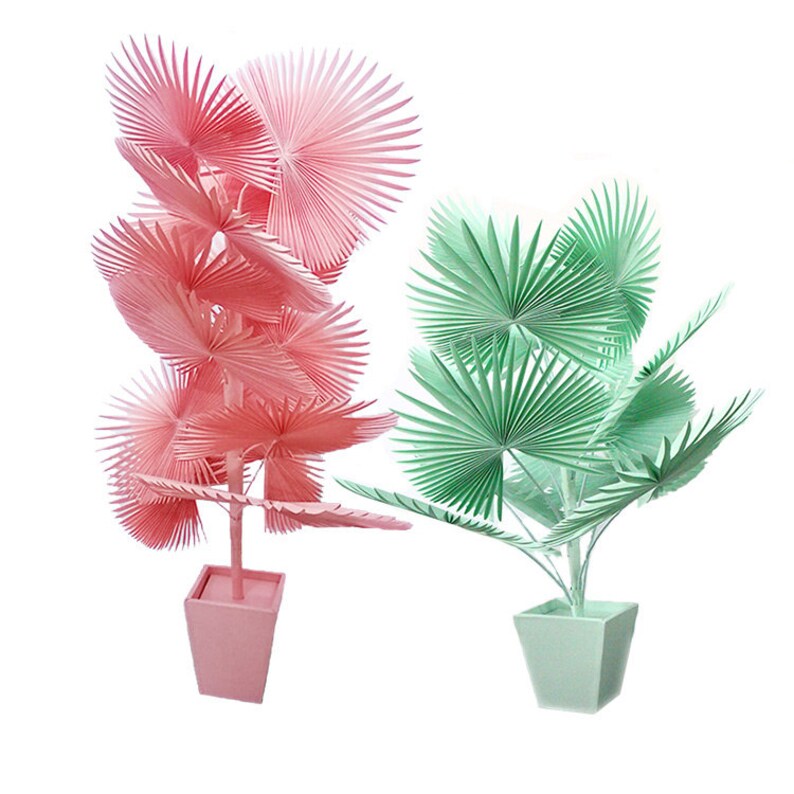 K&ouml;nnte beinhalten: Zwei k&uuml;nstliche Palmen im Topf, eine rosa und eine gr&uuml;n, mit f&auml;cherf&ouml;rmigen Bl&auml;ttern.