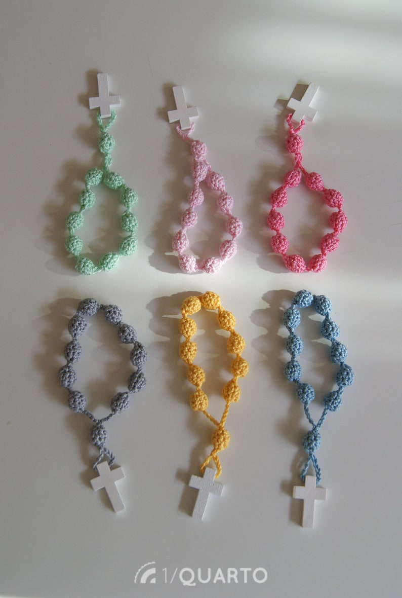 May include: Six crocheted rosaries with wooden crosses. The rosaries are in different colors: green, pink, red, gray, yellow, and blue.