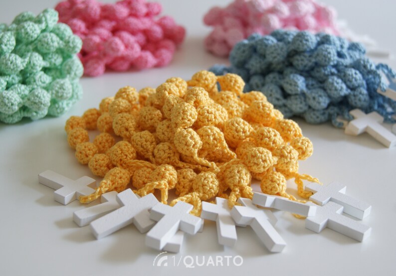 May include: Four sets of crocheted beads with wooden crosses. The beads are in shades of green, pink, blue, and yellow.