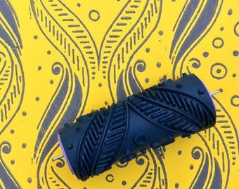May include: A black and grey patterned paint roller on a yellow background with a repeating pattern of black and grey swirls and circles.