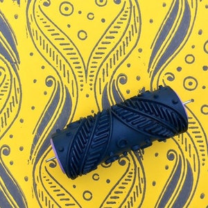 Può includere: Un rullo di vernice con motivo nero e grigio su uno sfondo giallo con un motivo ripetitivo di spirali e cerchi neri e grigi.