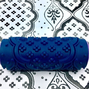 May include: A blue paint roller with a decorative pattern. The roller is designed to create a repeating pattern on walls or other surfaces.