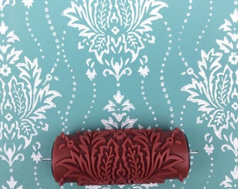 May include: A red paint roller with a damask pattern. The roller is designed to create a decorative pattern on walls.