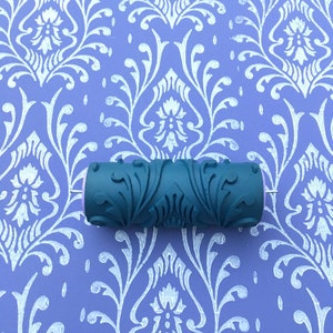 May include: A green paint roller with a decorative pattern of leaves and flowers. The roller is designed to create a damask pattern on walls.