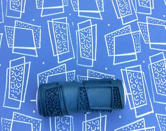 May include: A black and gray paint roller with a geometric pattern. The roller is on a blue background with a white geometric pattern.