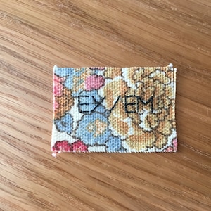 May include: A floral fabric label with the text "EX/EML" embroidered in black thread.