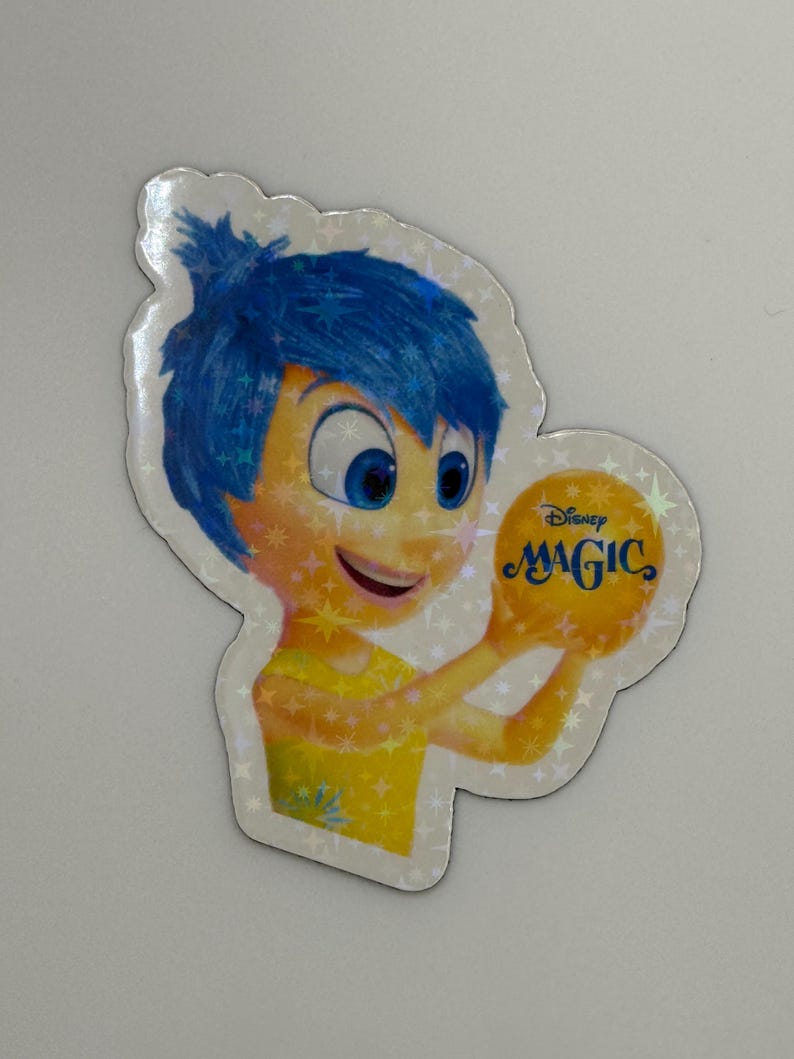 May include: A holographic sticker featuring the character Joy from the Disney Pixar movie Inside Out. Joy has blue hair and is holding a yellow orb with the word "MAGIC" on it. The sticker has a star-shaped border.
