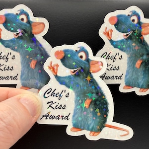 May include: Three stickers featuring a blue rat character with a chef's hat, with the text "Chef's Kiss Award". The rat is waving with a smile, and the stickers have a holographic, glittery effect.