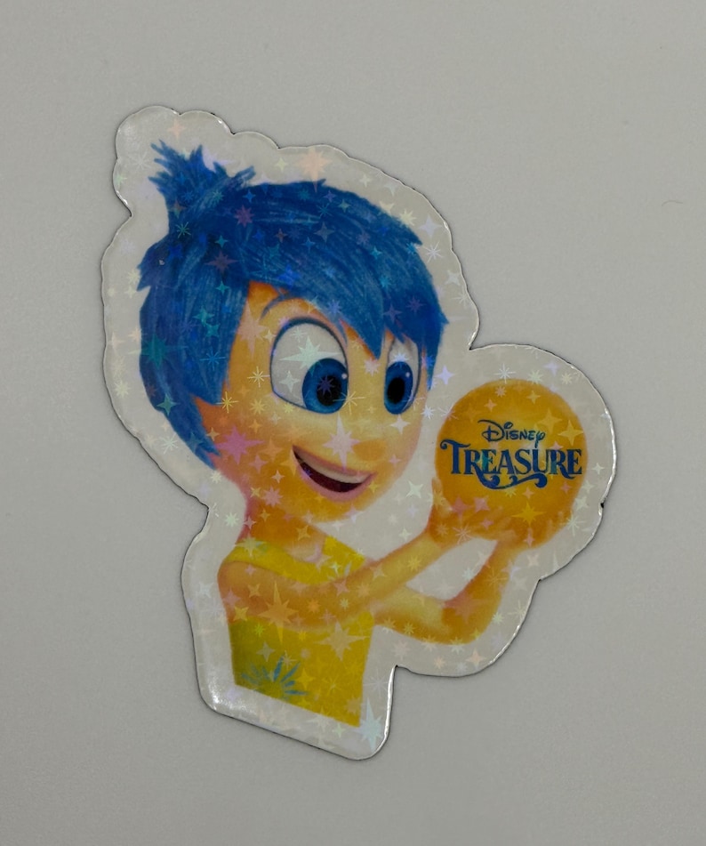 May include: A holographic sticker featuring the character Joy from the Disney movie Inside Out. Joy has blue hair and a yellow dress, holding a golden ball with the text "Disney Treasure". The sticker has a sparkly, iridescent finish.