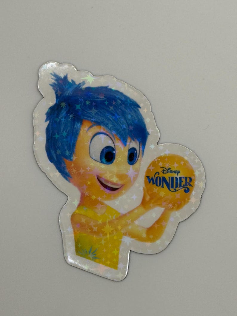 May include: A holographic sticker featuring the character Joy from the Disney movie "Inside Out." Joy has blue hair and a yellow outfit, holding a yellow orb with the word "Wonder" on it.