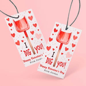 May include: Two Valentine's Day gift tags with a red shovel illustration and the text "I DIG YOU!" surrounded by red and pink hearts. The tags have a string for hanging and the text "Happy Valentine's Day From Jordan".