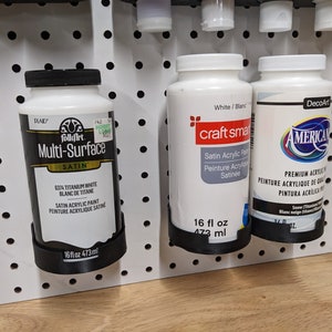 May include: Three bottles of white acrylic paint. The bottles are labeled "FolkArt Multi-Surface Satin", "Craft Smart Satin Acrylic Paint", and "DecoArt Americana Premium Acrylic Paint". Each bottle is 16 fluid ounces (473 ml).