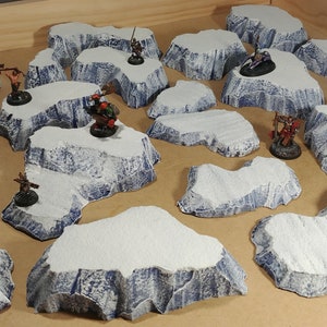 May include: A set of 13 snow-covered, blue-grey, rocky terrain pieces for tabletop gaming. The pieces are made of a lightweight material and are designed to be used as terrain features in a variety of games.