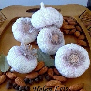 May include: Four crocheted garlic bulbs on a wooden tray with almonds and peppercorns. The text "Helen Leis" is visible on the tray.