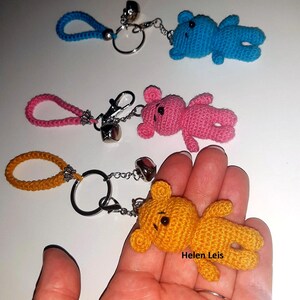 May include: Three crocheted teddy bear keychains with bells and key rings. The bears are blue, pink, and yellow.