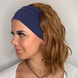May include: A navy blue headband made of soft fabric. The headband is worn by a person with brown hair.