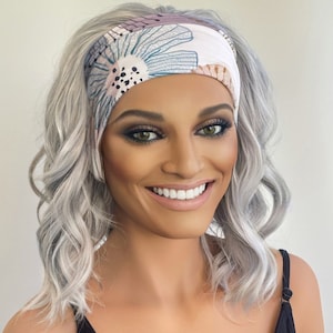 Könnte beinhalten: Eine Frau mit silbernem Haar trägt ein weißes Stirnband mit Blumenmuster. Das Stirnband hat blaue, rosa und braune Blumen mit schwarzen Punkten.