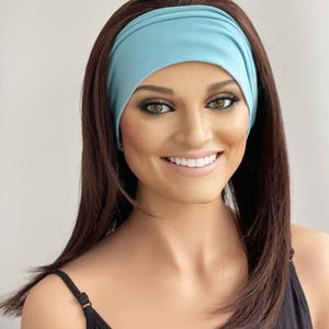 May include: A woman with long brown hair is wearing a light blue headband. The headband is made of a soft, stretchy fabric and is designed to be worn comfortably around the head.