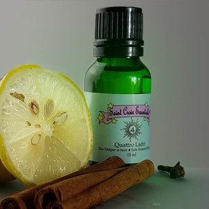 Może przedstawiać: Zielona szklana butelka z czarną zakrętką, z etykietą "Saint Croix Essentials" i "Quattro Ladri". Pokrojona cytryna, laski cynamonu i goździk ułożone wokół butelki. Butelka zawiera 15 ml bezpiecznej, naturalnej mieszanki.