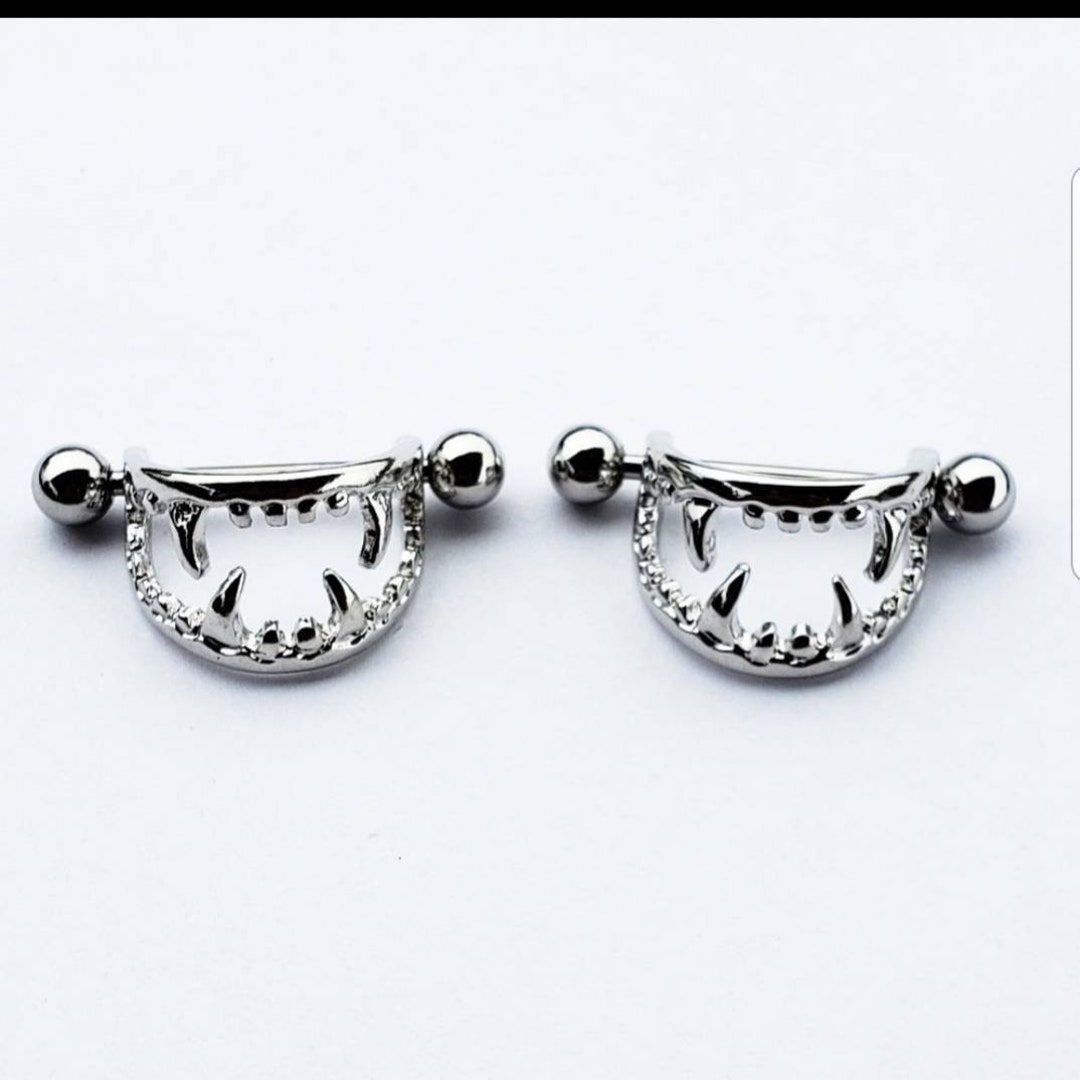 Silver coloured nipple piercing with vampire teeth shield
