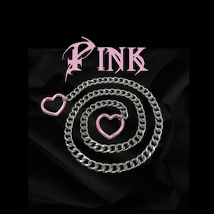 May include: A silver chain necklace with two pink heart charms. The chain is coiled and the word "PINK" is written in a stylized font above the chain.