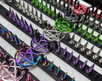 Könnte beinhalten: Fünf schwarze Lederhalsbänder mit Reihen von bunten Metallspikes. Jedes Halsband hat einen anderen schillernden Pentagramm-Anhänger.
