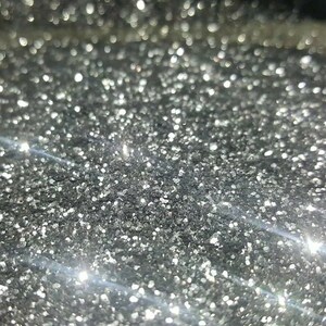 Op de afbeelding: Close-up van zilveren glitter met een glinsterend, reflecterend oppervlak.