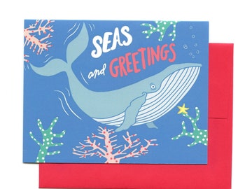 May include: A blue greeting card with a whale swimming in the ocean. The card says "Seas and Greetings" and has coral and seaweed in the background.