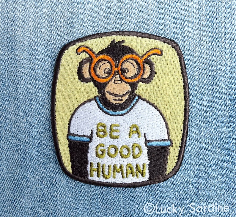 Pu&ograve; includere: Toppa ricamata da stirare con una scimmia dei cartoni animati che indossa occhiali con montatura arancione e una maglietta bianca con il testo "Be a good human".