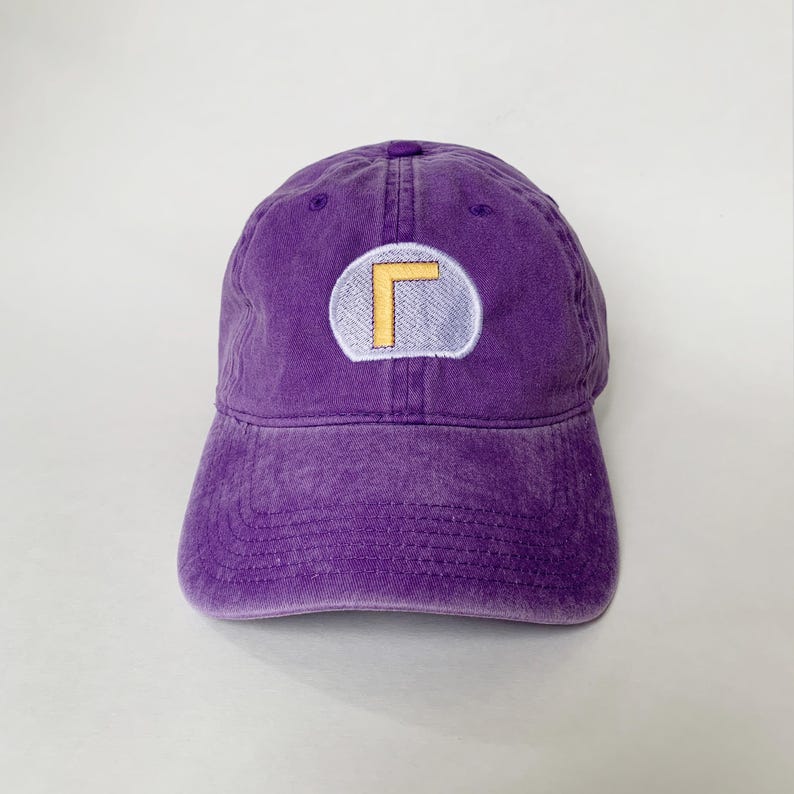 K&ouml;nnte beinhalten: Eine lila Baseballkappe mit verwaschenem, vintage Aussehen. Die Kappe hat einen runden Aufn&auml;her mit gelbem und wei&szlig;em Design. Der Hut ist aus weichem Material und hat einen gebogenen Schirm.