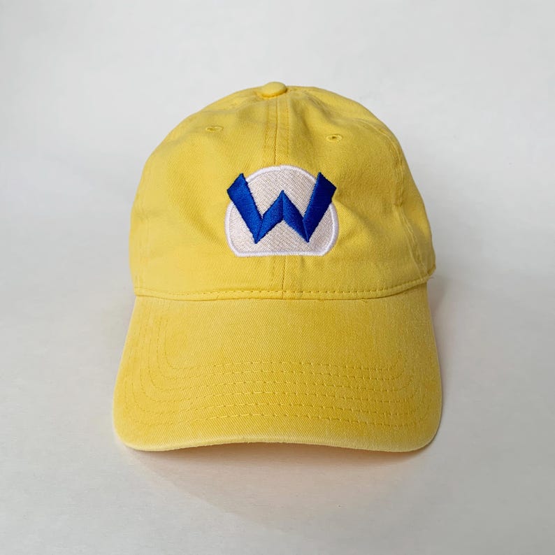K&ouml;nnte beinhalten: Gelbe Baseballkappe mit gebogenem Schirm. Die Kappe hat einen wei&szlig;en Aufn&auml;her mit einem blauen "W" auf der Vorderseite. Die Kappe ist aus einem weichen, strapazierf&auml;higen Material gefertigt.