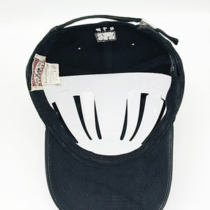 May include: Black baseball cap with a white interior and a red and white label that says "Maverick" on it.