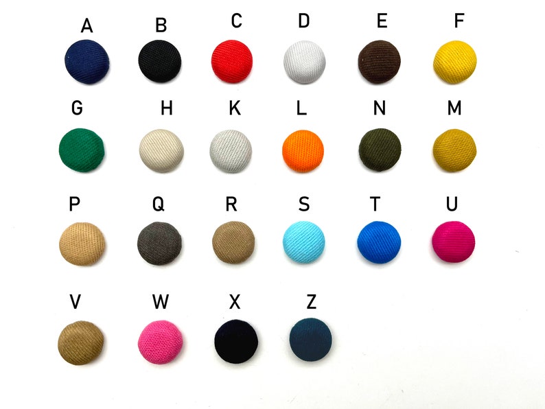 K&ouml;nnte beinhalten: Sortiment von 26 runden Kn&ouml;pfen in verschiedenen Farben und Stoffen, beschriftet mit den Buchstaben A bis Z.