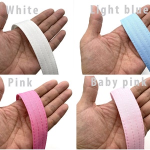 May include: Four different colors of fabric ribbon with a stitched edge. The colors are white, light blue, pink, and baby pink.