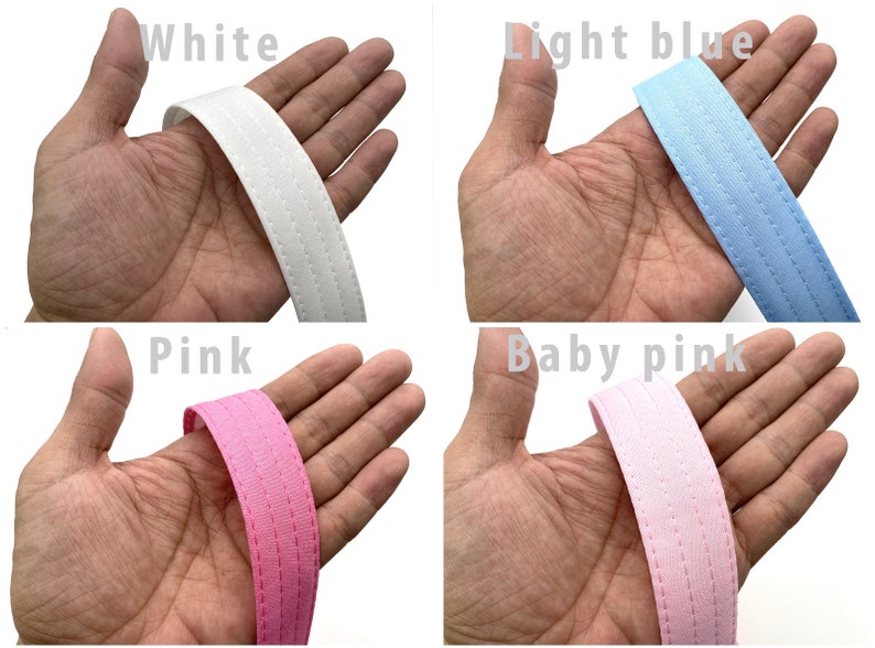 May include: Four different colors of fabric ribbon with a stitched edge. The colors are white, light blue, pink, and baby pink.