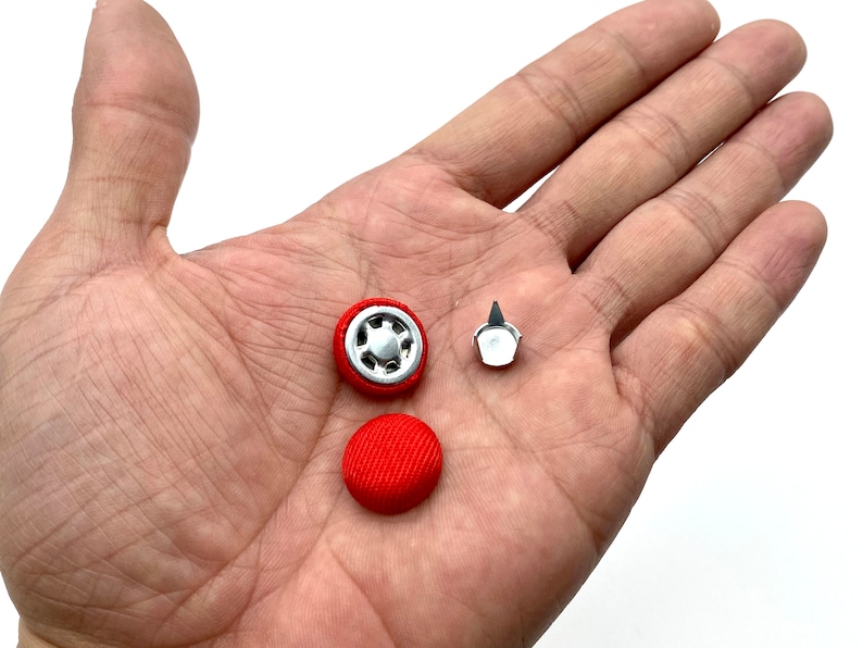 K&ouml;nnte beinhalten: Drei rote und silberne Kn&ouml;pfe, zwei sind rund und einer ist ein spitzer Knopf.
