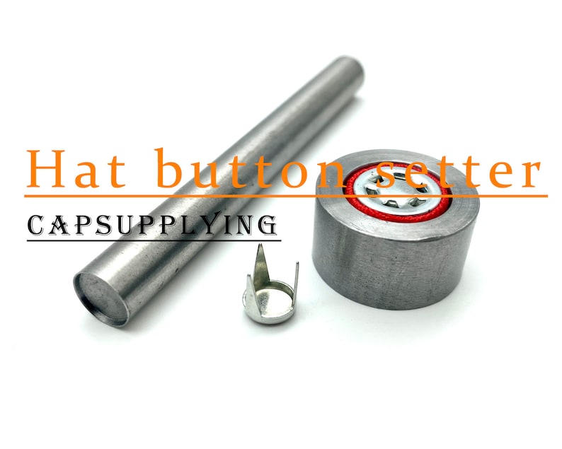 K&ouml;nnte beinhalten: Ein silberner Hutknopf-Setzwerkzeug mit einem roten und silbernen Knopf und einem silbernen Knopfschaft. Das Werkzeug ist mit "Hat button setter" und "CAPSUPPLYING" beschriftet.