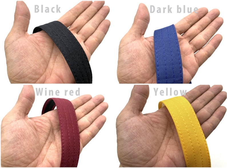 May include: Close-up of four fabric straps in different colors: black, dark blue, wine red, and yellow. Each strap has a double stitched seam.