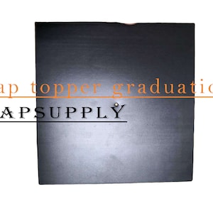 May include: A black square cap topper for graduation. The text "Cap topper graduation" and "CAPSUPPLY" are printed on the image.