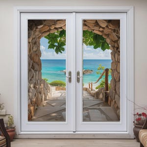 May include: White double doors with a view of a stone archway leading to a beach with turquoise water and blue sky. The archway is made of stacked stones, and green leaves are visible.